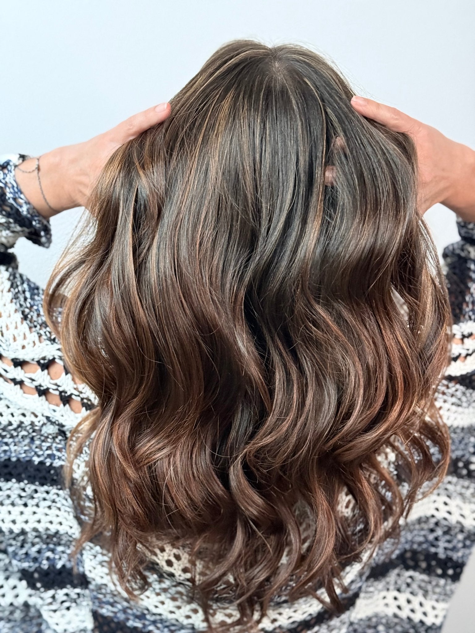 a woman with brunette hair and caramel honey highlights with a white background