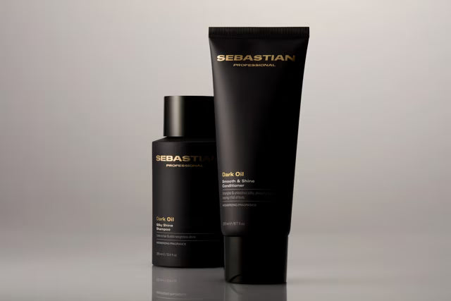 Black bottles of Dark Oil Shampoo and Conditioner and a shadowed backdrop