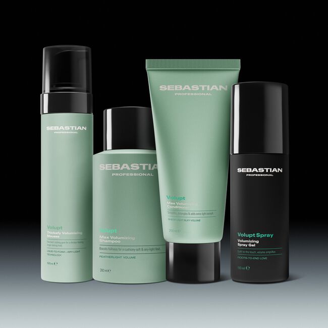 Four Sebastian Professional haircare bottles and tubes arranged together on a dark studio background. The set includes a tall pump bottle, a short bottle, a squeeze tube, and a cylindrical spray bottle, in pale mint green and black packaging.