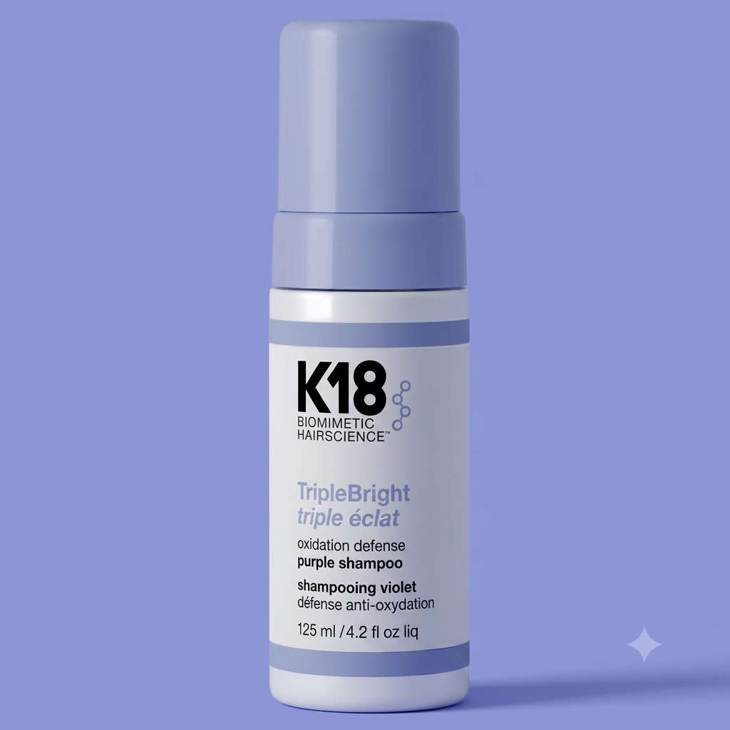 A bottle of K18 Biometric Hairscience TripleBright Triple purple shampoo, featuring a white bottle with lavender-blue accents and a matching cap, set against a solid lavender-blue background.