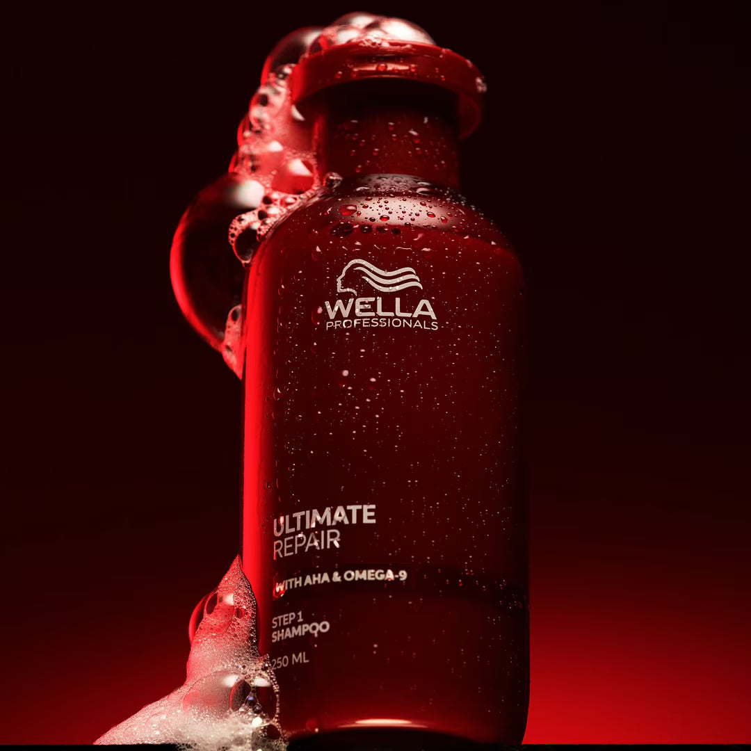 Red Wella shampoo bottle with water droplets on a black background