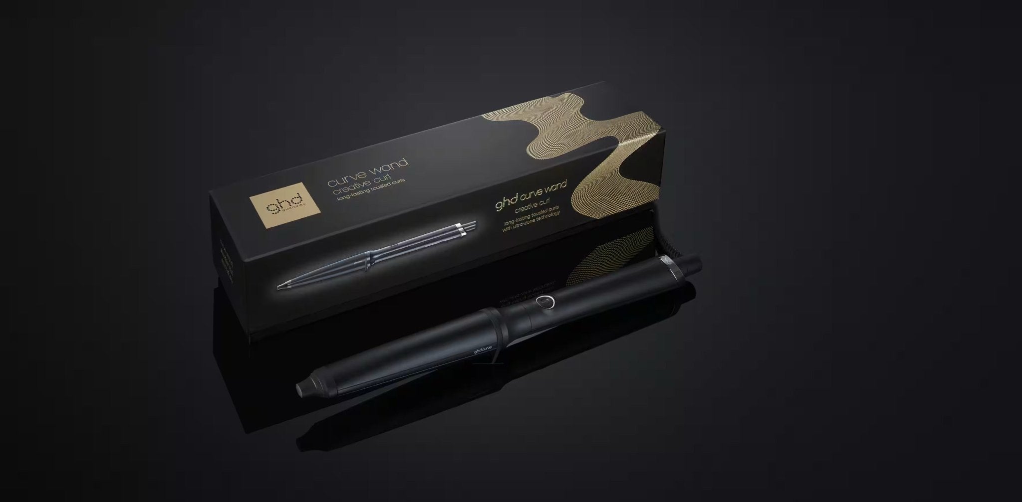 The GHD CREATIVE CURL - TAPERED CURLING WAND IN BLACK by GHD, with its sleek gold-accented packaging, rests against a dark background. Its tapered barrel is perfect for creating effortless beachy waves.