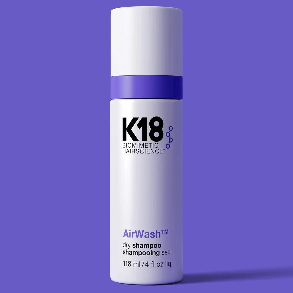 A 118 ml bottle of K18 AirWash Dry Shampoo by K18 Hair Repair, featuring odorBIND™ biotechnology, is shown against a solid purple background.