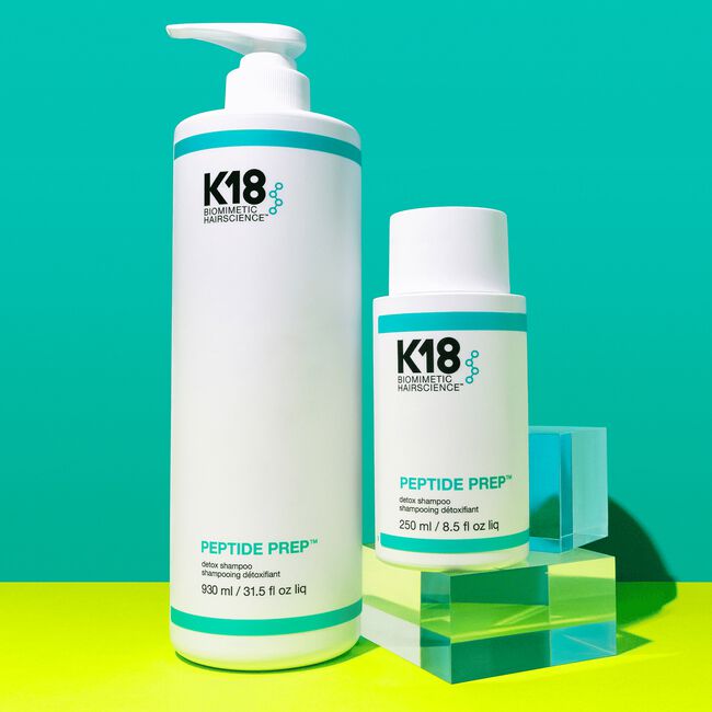 Two K18 hair care products on a green and blue gradient background