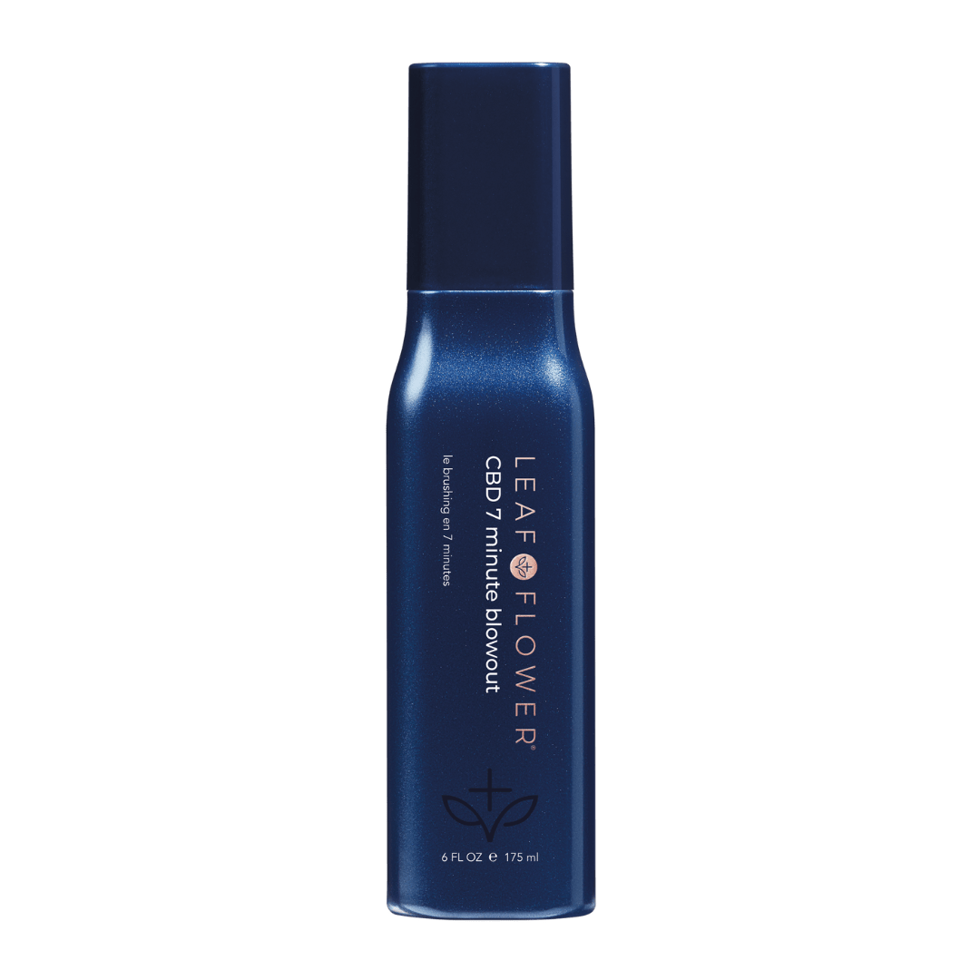 A dark blue bottle labeled "Leaf and Flower 7 Minute Blowout" with white text, a small graphic near the bottom, and a navy cap. This 6 fl. oz. spray by Leaf and Flower smooths frizz for a sleek, fast blowout finish in just 7 minutes.