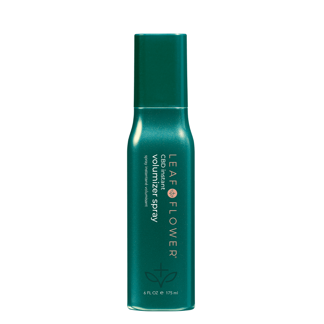 A green, cylindrical bottle of LEAF and FLOWER Instant Volumizer Spray stands upright on a white background. The label displays the Leaf and Flower brand name and details promoting plant-derived technology for fuller-looking hair.