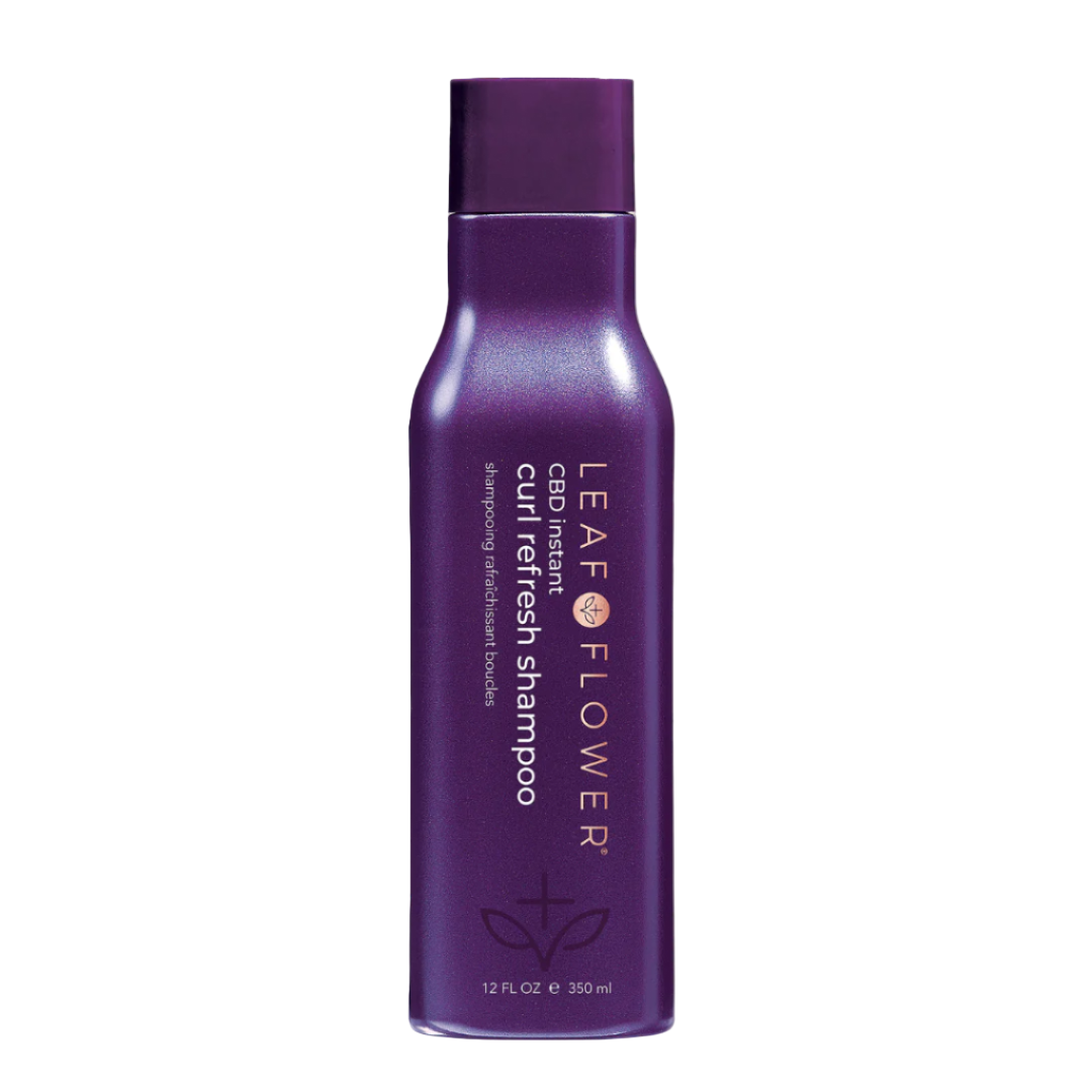 A purple bottle of Leaf and Flower Instant Curl Refresh Shampoo (multiple sizes available) with gold text stands upright against a light background. This color-safe formula from Leaf and Flower is perfect for reviving curls.