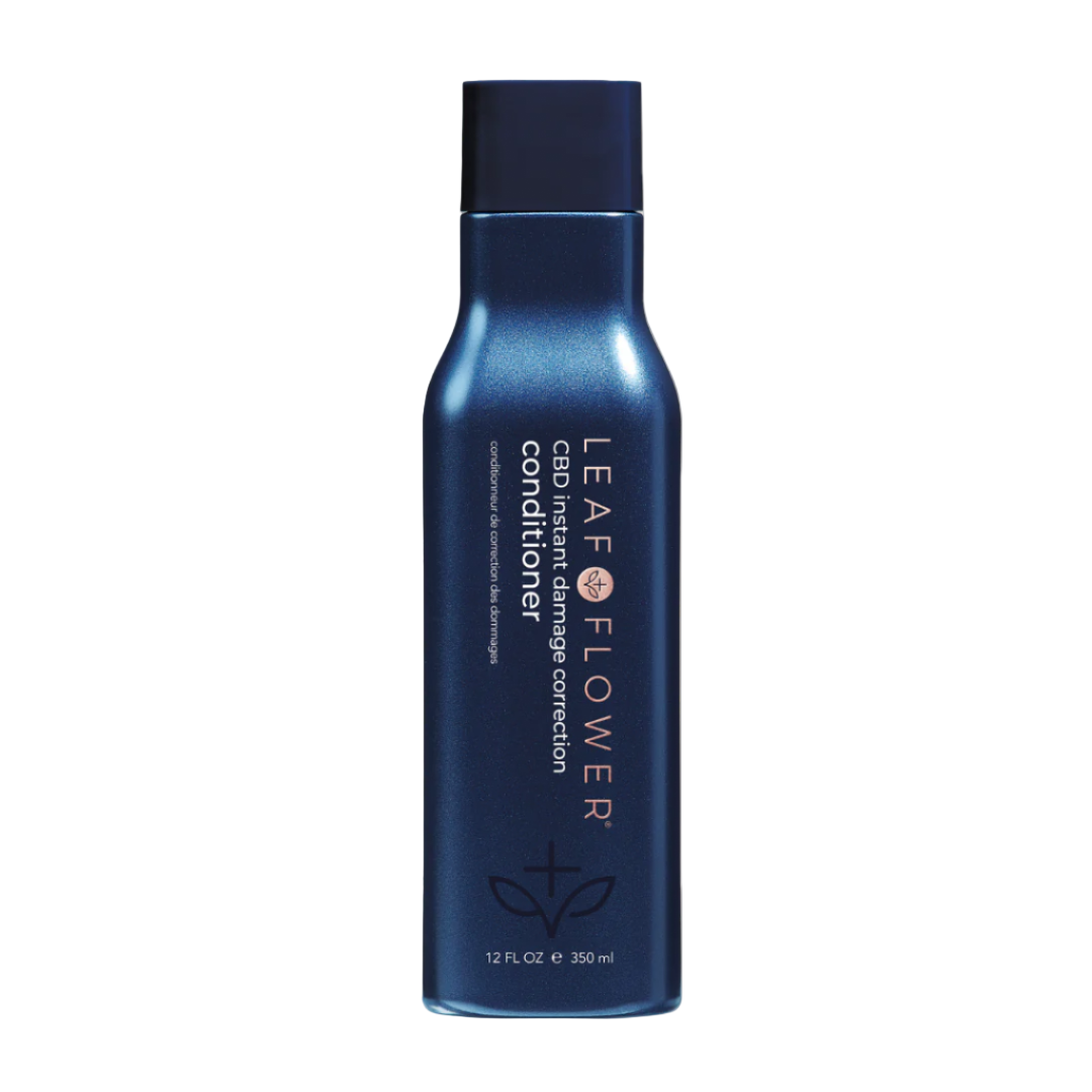 A blue bottle of Leaf and Flower Damage Correction Conditioner (multiple sizes available) stands upright against a light beige background, featuring white text, a plant graphic, and highlighting its cruelty-free, plant-based formula.