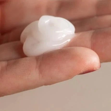 A close-up of a hand holding Oway Frequent Use Conditioner, a lightweight conditioner by Oway, ideal for daily use and suitable for all hair types, against a neutral background.
