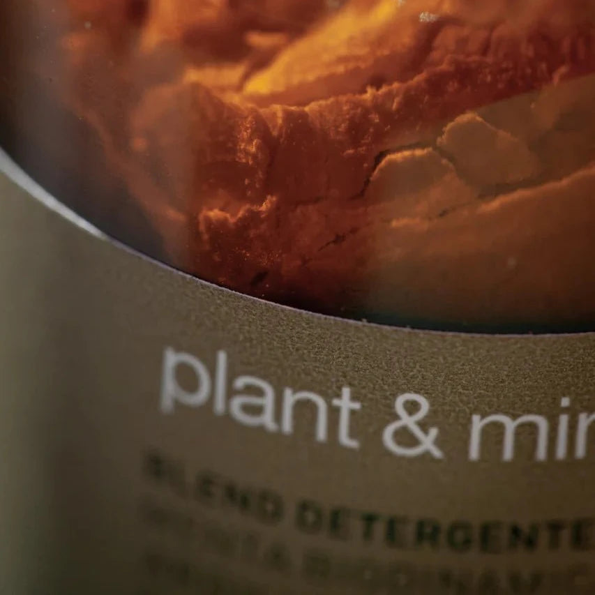 A close-up of a brown glass bottle labeled "plant & min." The product is Oway Plant & Mineral Refresh, a purifying dry shampoo powder for all hair types. The text beneath the label appears blurred and unreadable.