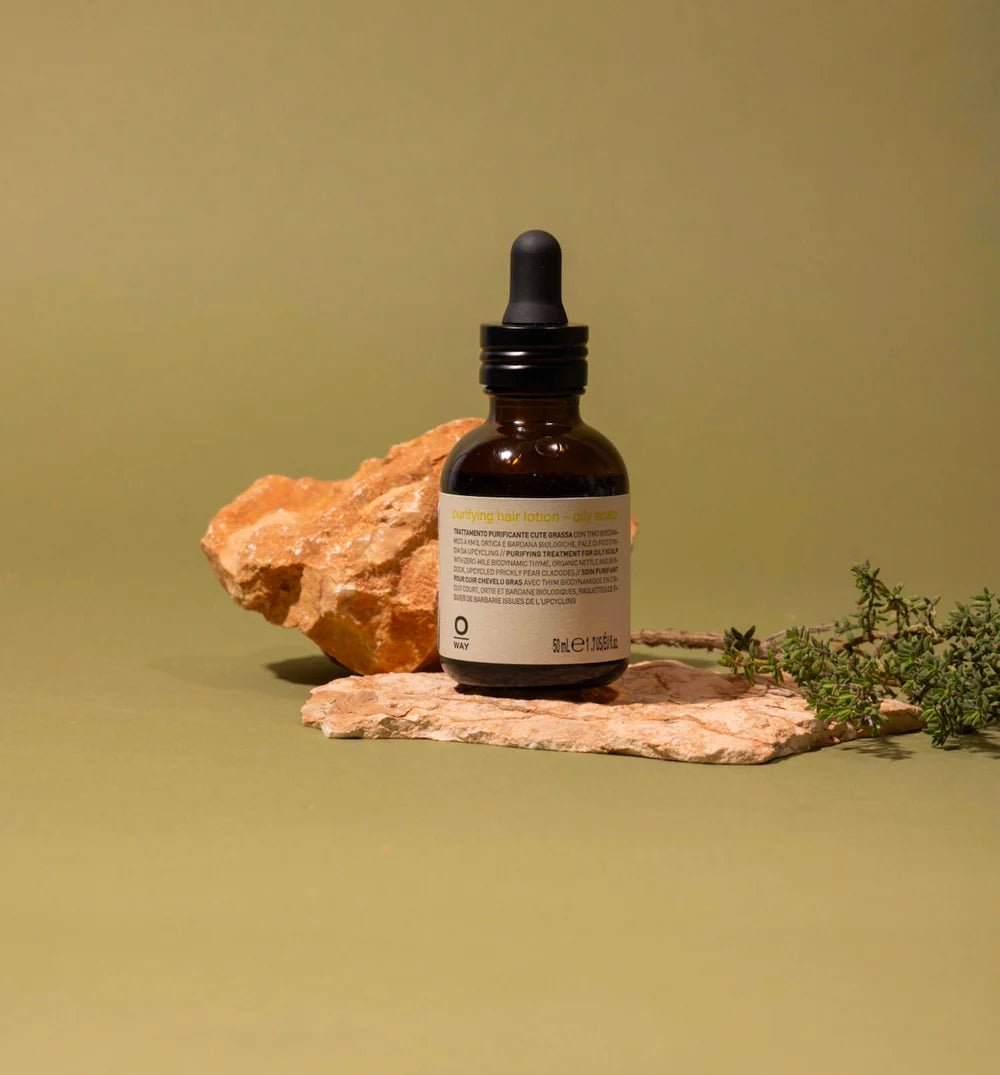Brown glass dropper bottle with label on a rock against a green background