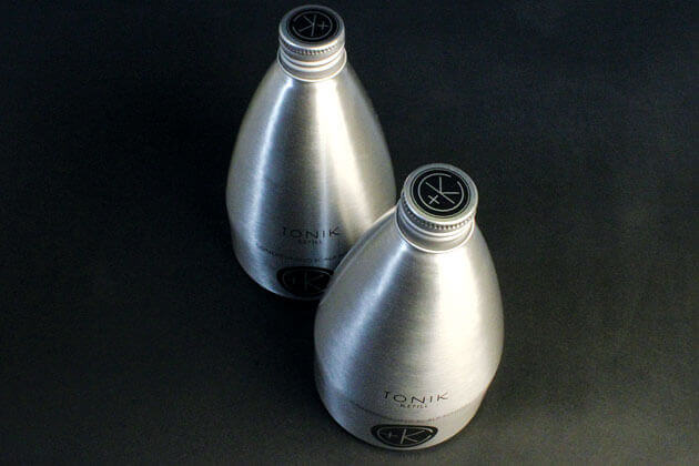 Two silver bottles of Cult and King TONIK, also known as Conditioning Hair & Scalp Potion, are placed on a black surface.