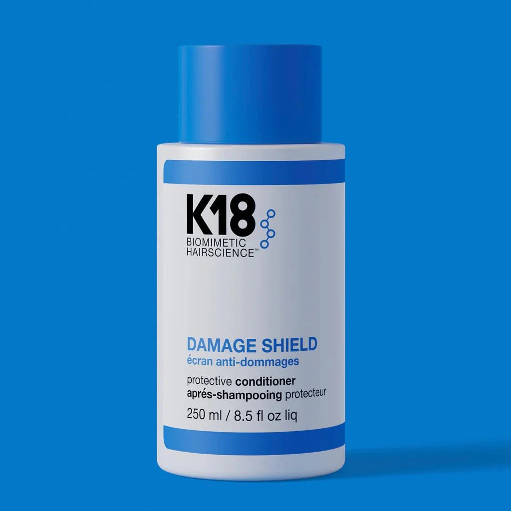 A 250 ml bottle of K18 Hair Repair Damage Shield pH Protective Conditioner, featuring K18PEPTIDE™, is displayed against a solid blue background.