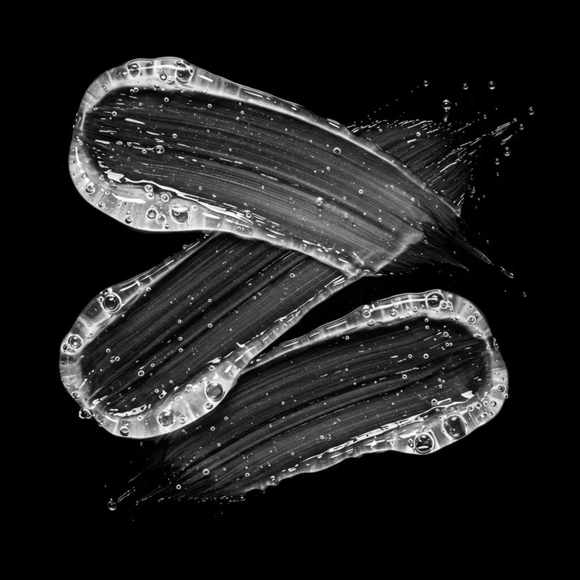 Volupt clear shampoo smears with a thick viscosity on a black background. 