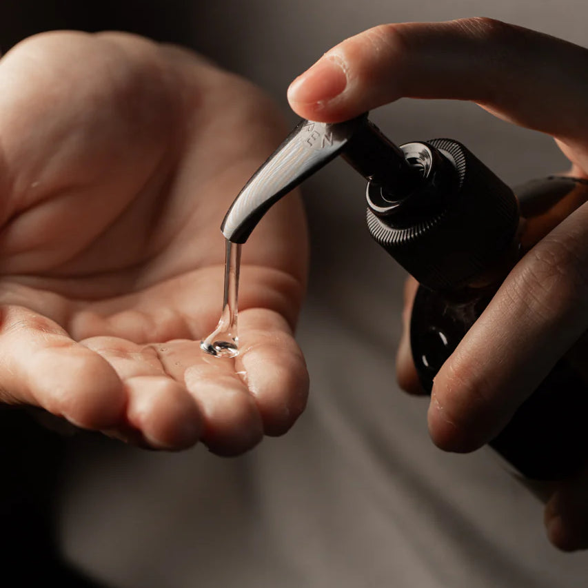 A person dispenses Oway Flux Potion Lightweight Volumizing Serum, infused with Marula Oil, from a pump bottle onto their open palm.