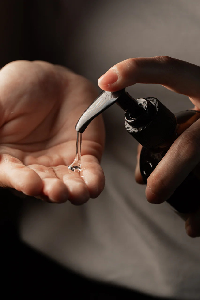 A person dispenses Oway Flux Potion Lightweight Volumizing Serum, infused with Marula Oil, from a pump bottle onto their open palm.