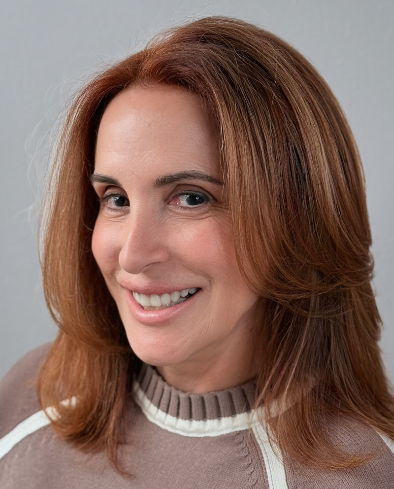 Woman with shoulder-length brown hair wearing a brown sweater with a white collar against a gray background