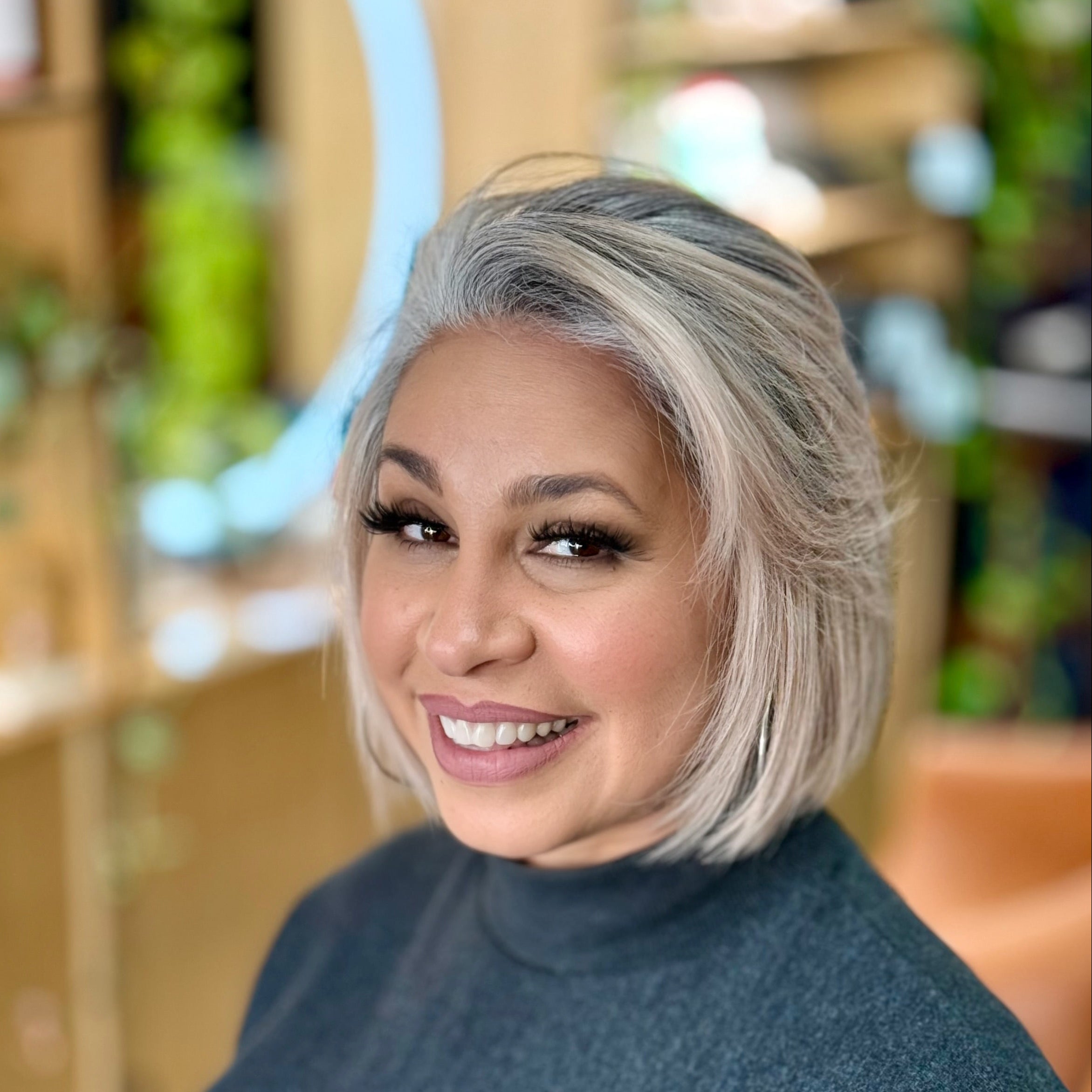 Woman with short gray hair wearing a blue turtleneck sweater in an indoor setting.
