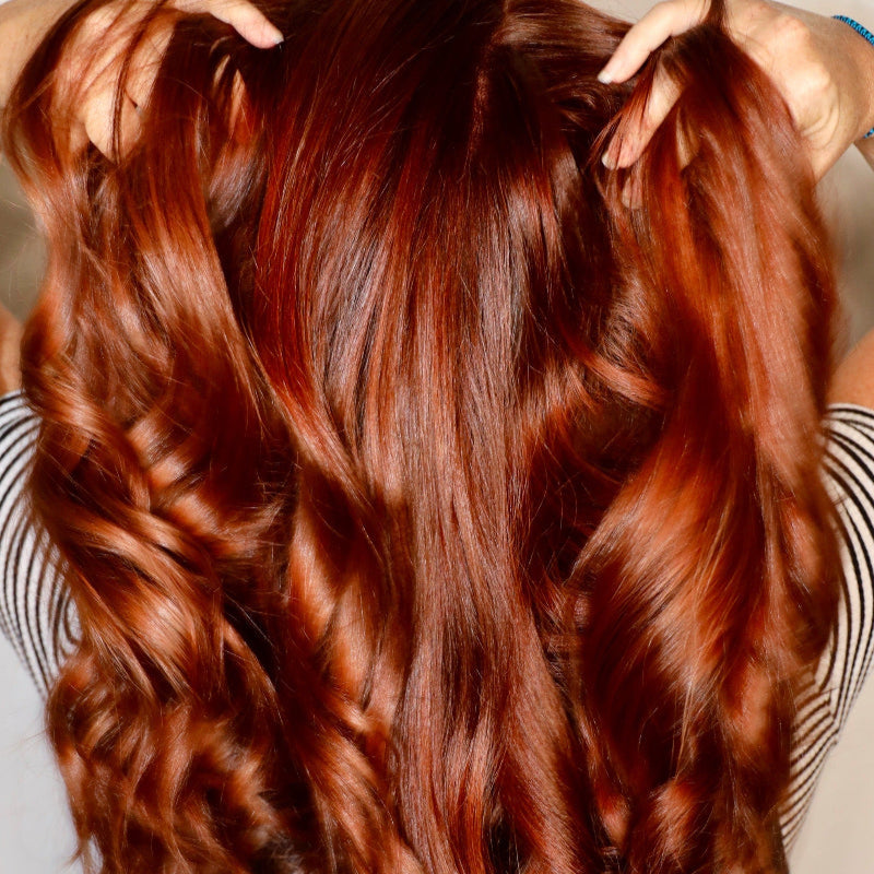 Close-up of a person with long, wavy red hair.
