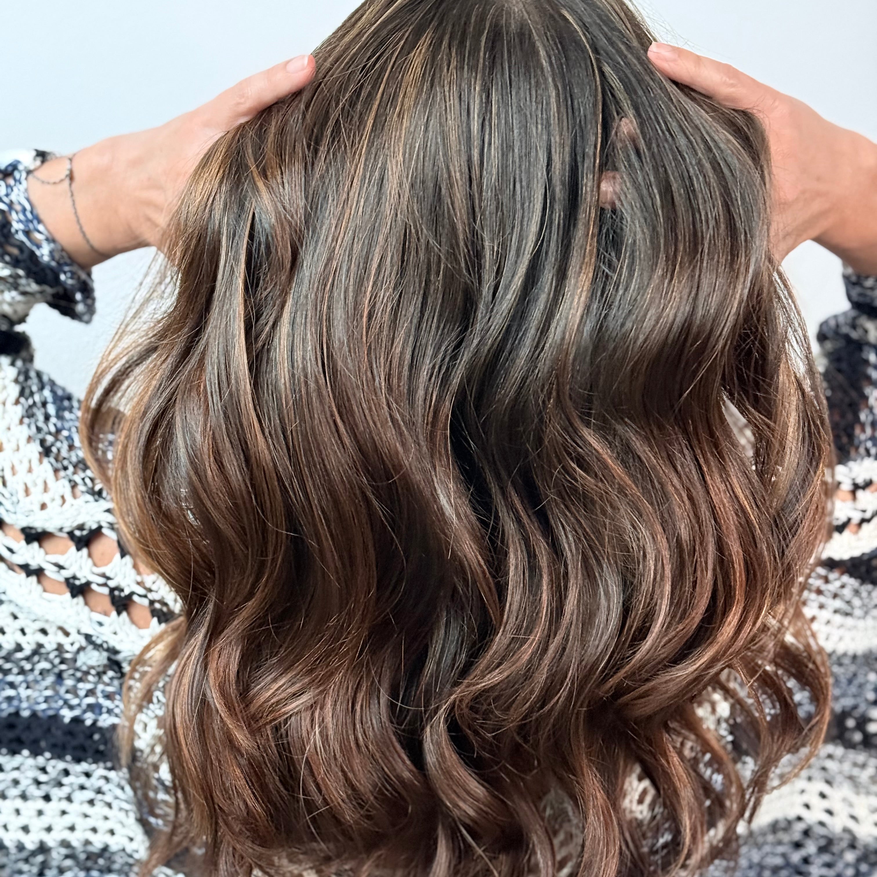 Person with wavy brown hair against a light background