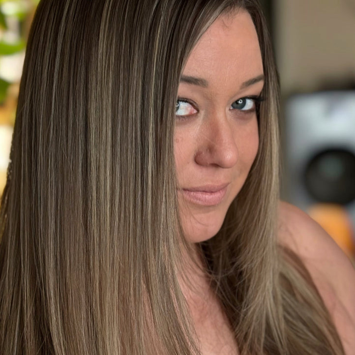 Woman with long brown hair looking to the side with a blurred background