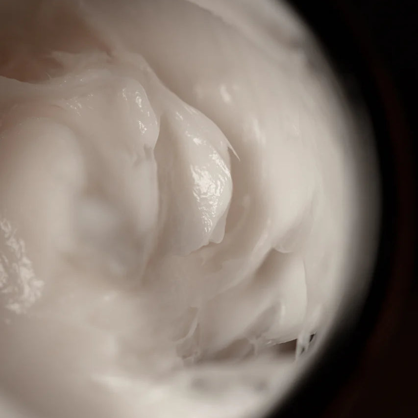 A close-up of Oway Shaping Putty, a creamy white styling putty by Oway, provides medium hold and a natural finish for sculpted texture inside its container.