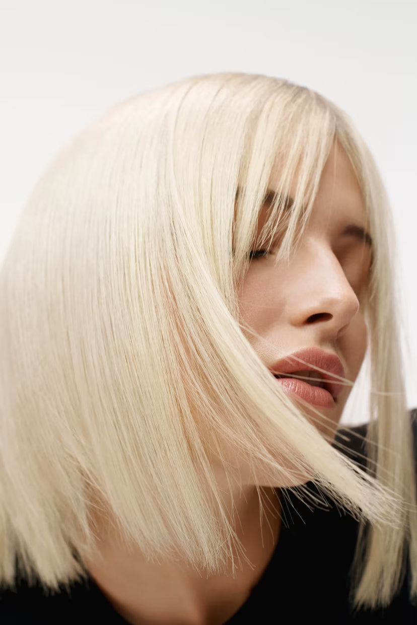 Close-up of a person with long, straight blonde hair against a neutral background