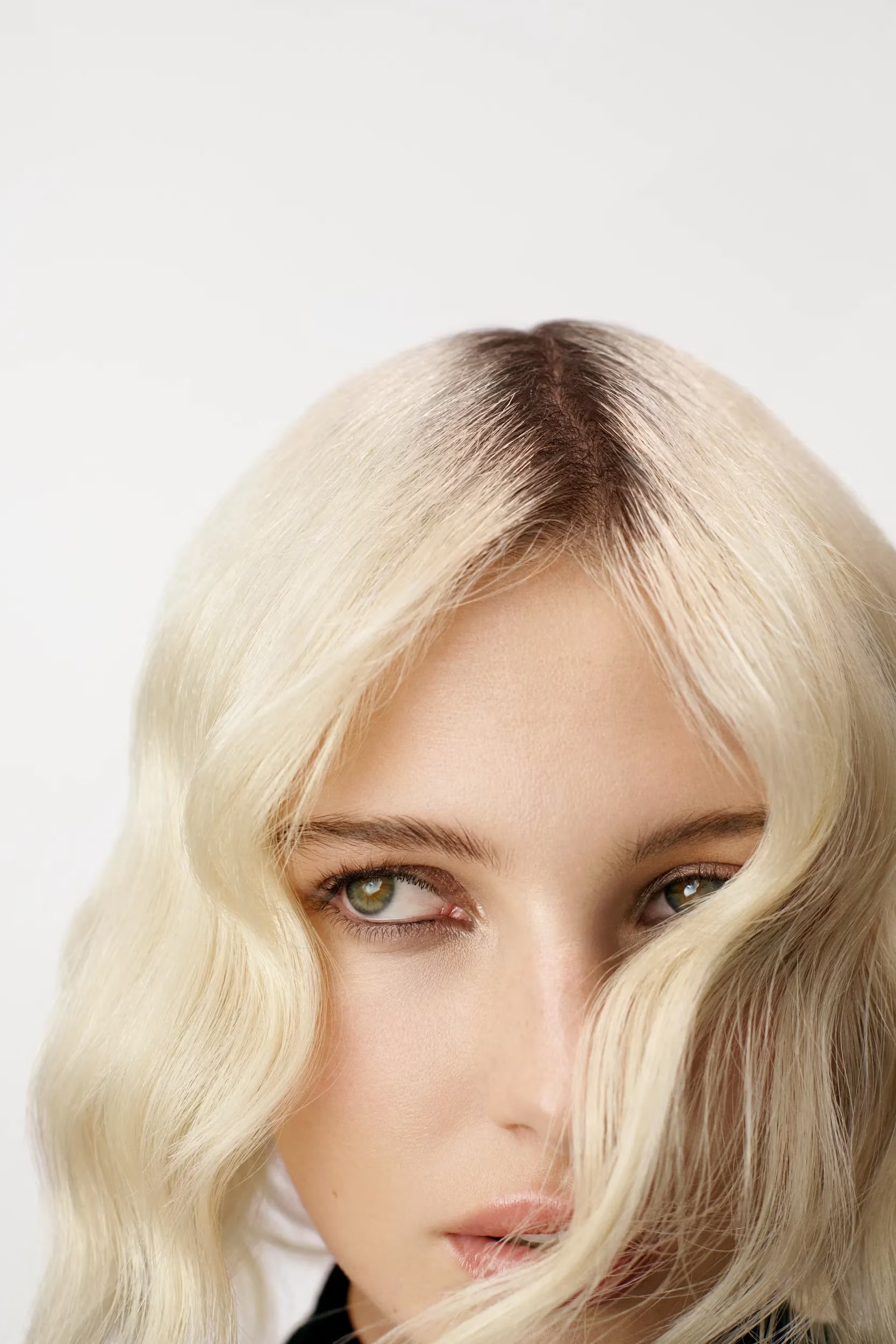 Close-up of a person with blonde hair and green eyes on a white background