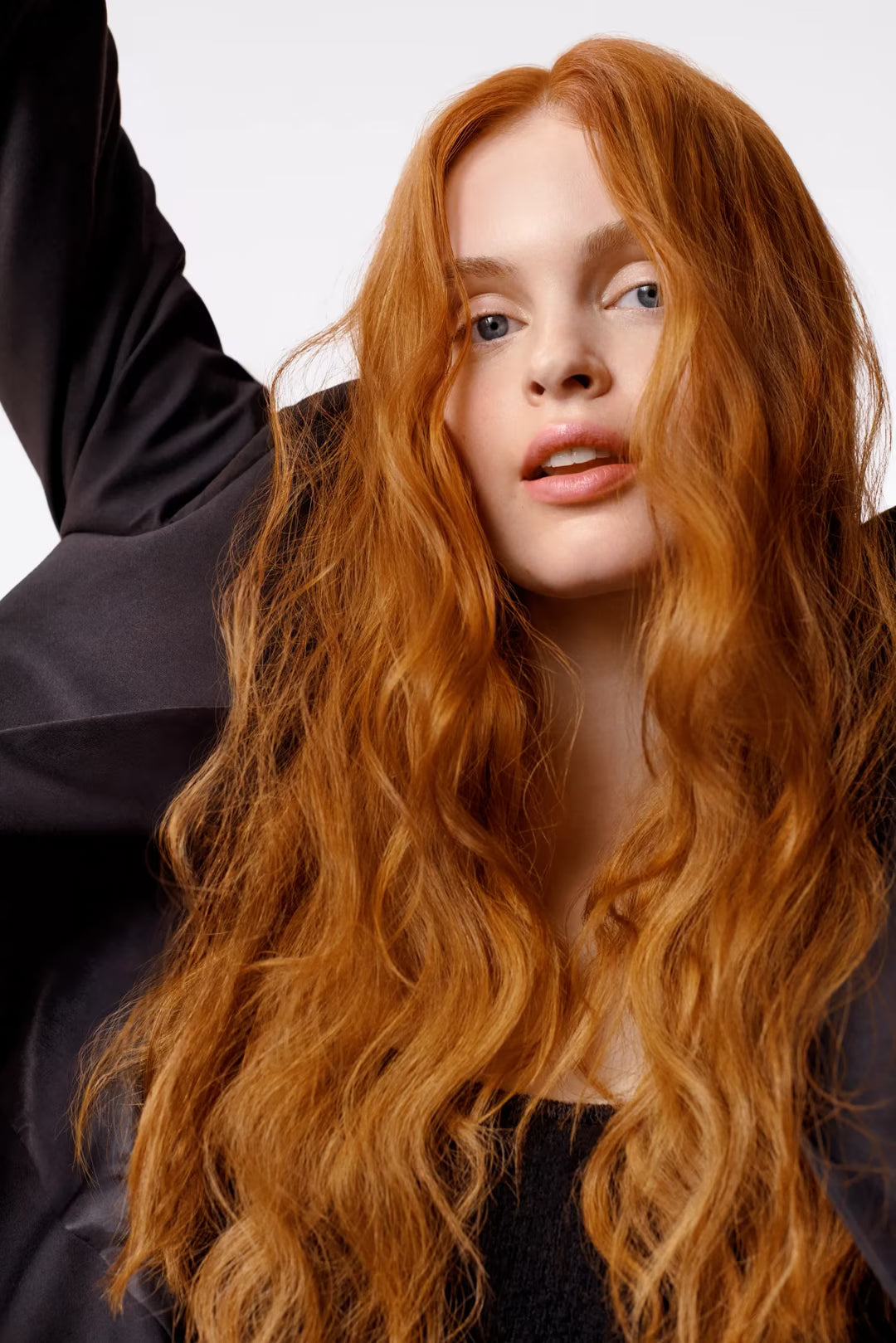 Woman with long wavy red hair against a neutral background