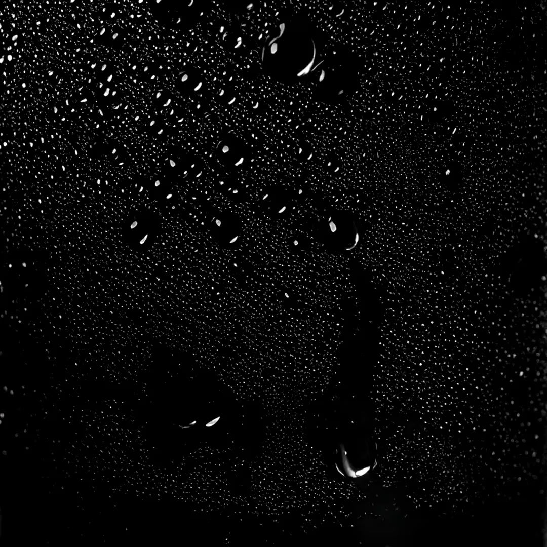 Close-up of Sebastian Professional Volupt Max Volumizing Spray Gel droplets on a glass surface with a black background