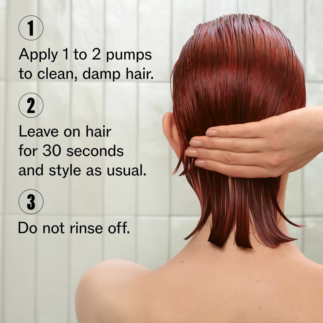 Person with red hair applying a product to their hair, with instructions on a white tiled wall background.