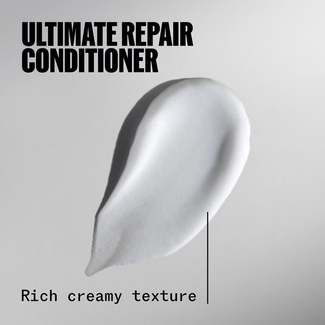 Rich creamy texture of ultimate repair conditioner on a gray background