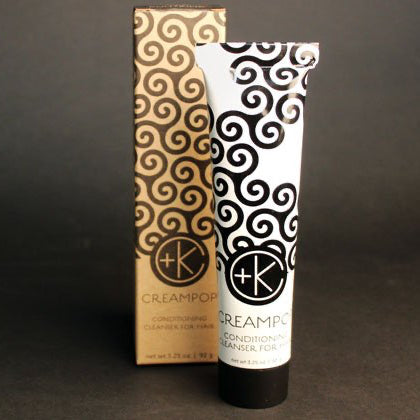 A tube and box of Cult and King CREAM POP Conditioning Cleanser for Hair, with black swirl designs on light backgrounds, are displayed upright on a dark surface—ideal for clean, shiny hair enriched with natural oils.