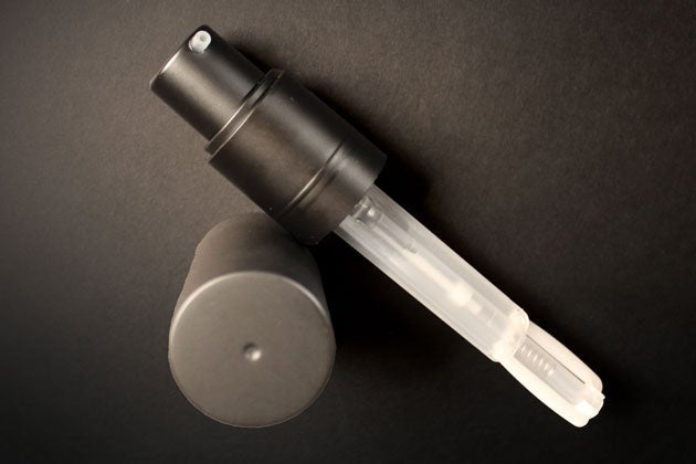 A black and clear spray bottle set against a dark background, with the cap removed and placed next to it, exudes elegance. Its sleek design suggests it contains Cult and King's PUMPABLE HAIR POWDER—a talc-free dry shampoo that adds volume and transforms your beauty routine with its antioxidant-rich formula.