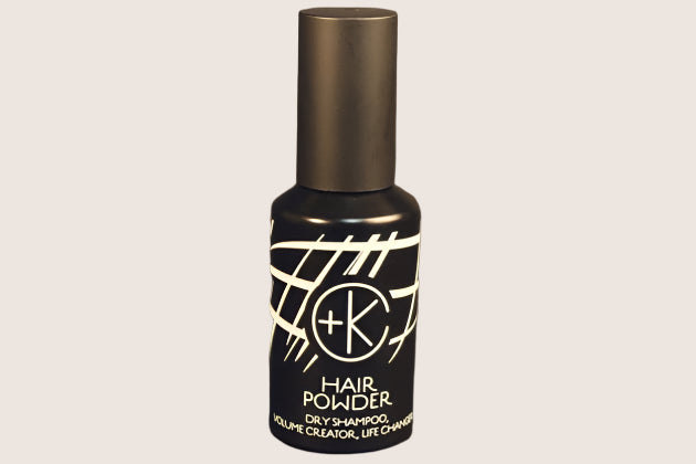 A dark bottle of "Cult and King PUMPABLE HAIR POWDER" showcases white abstract patterns against a sleek black backdrop. This talc-free, antioxidant-rich formula is boosted with Kaolin clay to ensure refreshed, revitalized hair without the added weight.