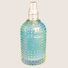 The Cult and King SET SPRAY, a Semi-Precious Tri-Phase Wonderworking Hairspray by Cult and King, comes in a blue-green glass bottle with a silver spray nozzle and a textured, dotted surface. The front of the bottle is embossed with a logo featuring a plus sign. Infused with Malachite Extract, this formulation also provides heat protection. The background is black.