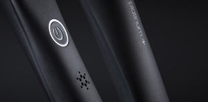 Close-up of the GHD PLATINUM+ STYLER 1" flat iron in black, featuring a power button and "platinum+" displayed on its surface.