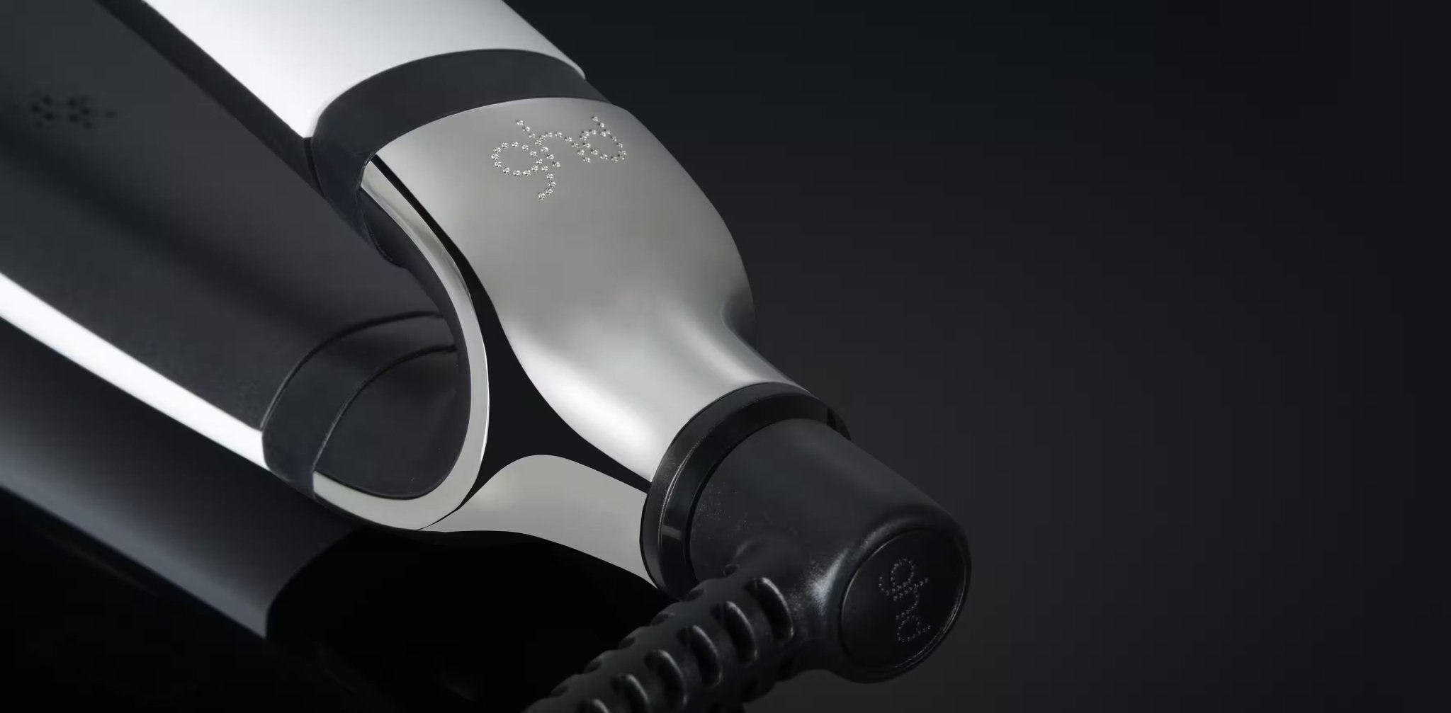 Close-up image of a sleek black and silver hair straightener, featuring the letters "ghd" on its side. This smart styler delivers personalized results for smooth, glossy locks or effortless flat iron waves - the GHD PLATINUM+ STYLER - 1" FLAT IRON by GHD.