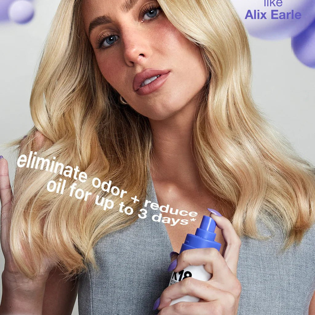 A person with long blonde hair holds a bottle of K18 AirWash Dry Shampoo by K18 Hair Repair. Text on the image reads "eliminate odor + reduce oil for up to 3 days".