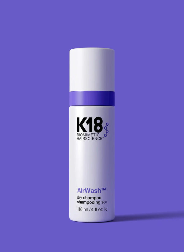 A 118 ml bottle of K18 AirWash Dry Shampoo by K18 Hair Repair, featuring odorBIND™ biotechnology, is shown against a solid purple background.