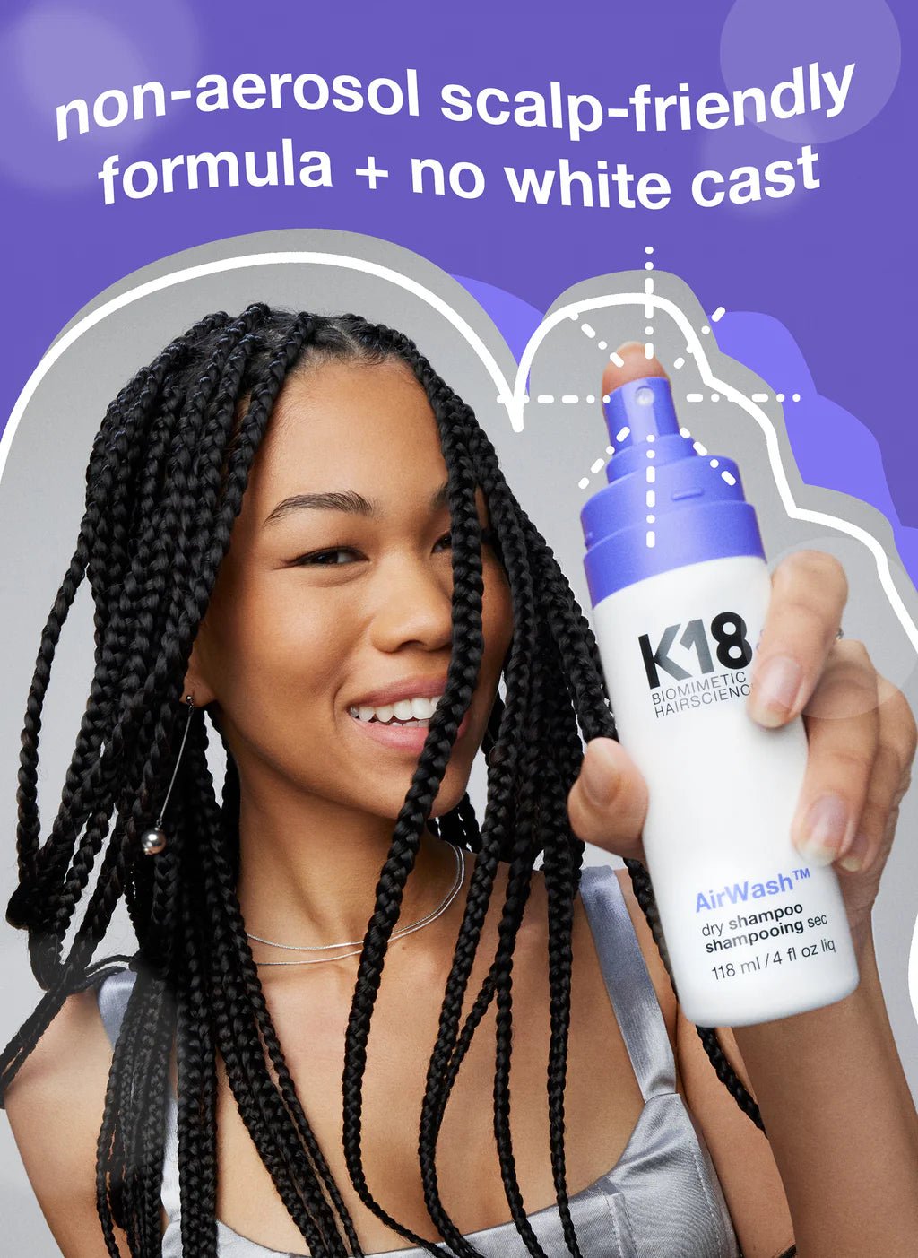 A woman smiling and holding a bottle of K18 AirWash Dry Shampoo, a non-aerosol, scalp-friendly dry shampoo featuring odorBIND™ biotechnology from K18 Hair Repair. The text on the image highlights its formula that leaves no white cast and promotes scalp health.
