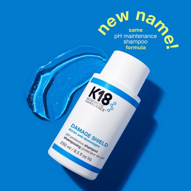 K18 Damage Shield shampoo bottle with blue shampoo sample on a blue background