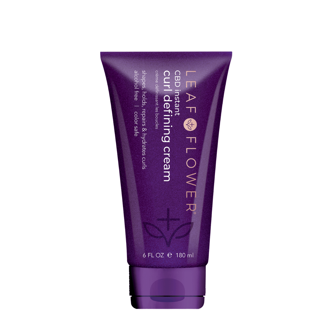 A purple 6 fl oz (180 ml) tube labeled "Leaf and Flower Instant Curl Defining Cream" features white and gold text, a leaf design, and promises frizz-free curls with its plant-based bio-adhesive formula.