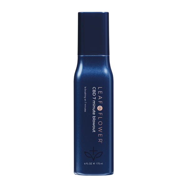 A dark blue bottle labeled "Leaf and Flower 7 Minute Blowout" with white text, a small graphic near the bottom, and a navy cap. This 6 fl. oz. spray by Leaf and Flower smooths frizz for a sleek, fast blowout finish in just 7 minutes.