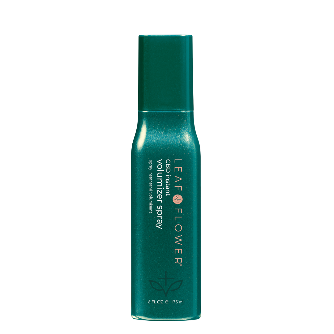 A Leaf and Flower Instant Volumizer Spray with a lid on a black surface.