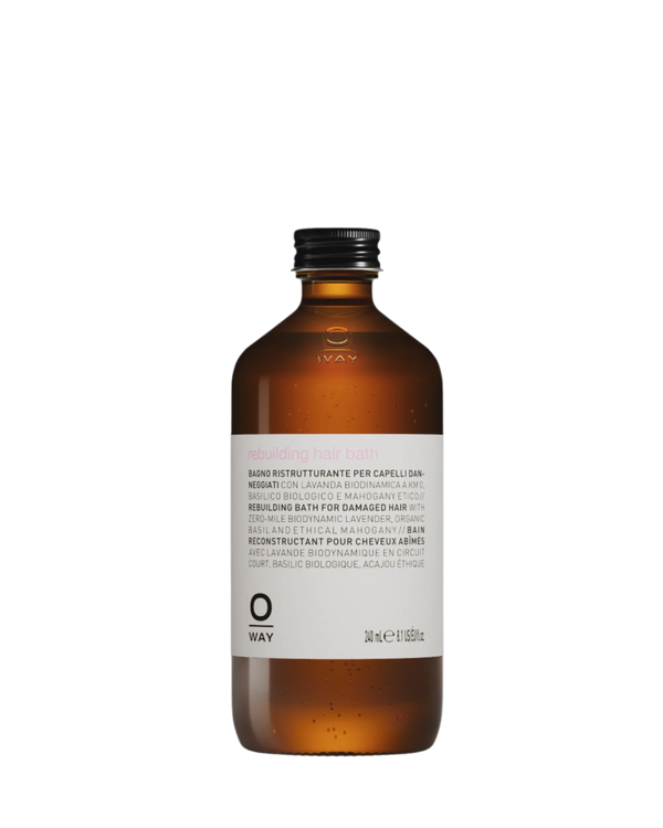 A brown bottle with a black cap labeled "Oway Rebuilding Hair Bath | Strengthening Shampoo for Brittle, Weak Hair" features multilingual product details and indicates a volume of 240 ml.