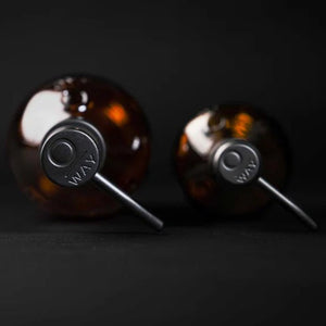 Two Oway Reusable Metal Pump Dispensers from Simply Colour Hair Salon Studio & Online Store are placed on a black surface. Viewed from above, the minimalistic composition and dark background emphasize their eco-friendly, reusable design.