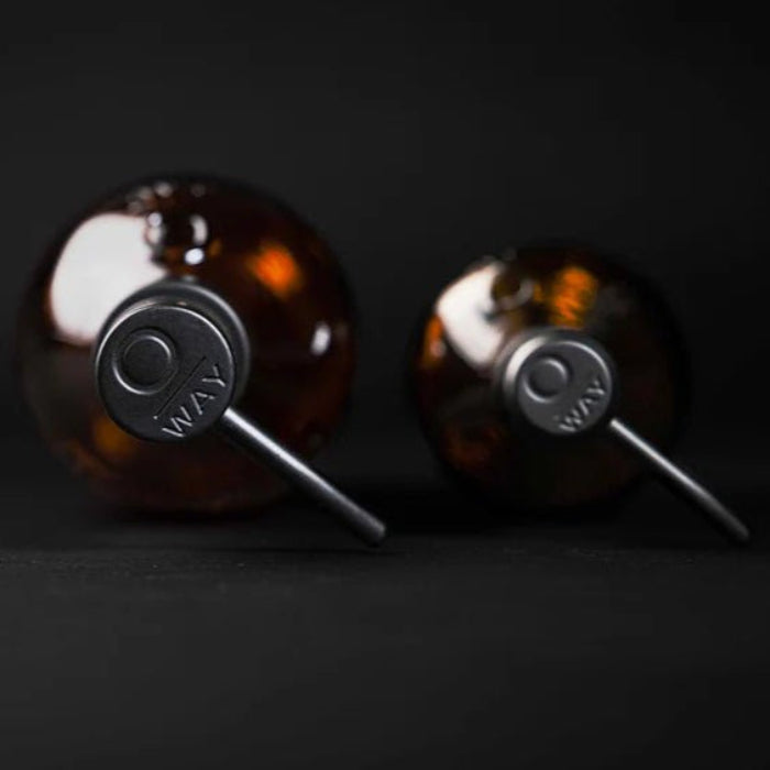 Two Oway Reusable Metal Pump Dispensers from Simply Colour Hair Salon Studio & Online Store are placed on a black surface. Viewed from above, the minimalistic composition and dark background emphasize their eco-friendly, reusable design.