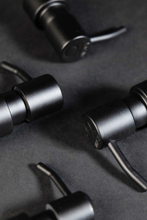 Close-up of four Oway Reusable Metal Pump Dispensers by Simply Colour Hair Salon Studio & Online Store, arranged diagonally on a dark surface.