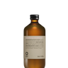 A brown Oway Smoothing Conditioner bottle, designed for frizzy hair with biodynamic caraway, features a silver cap and minimalistic look, set against a black textured background.